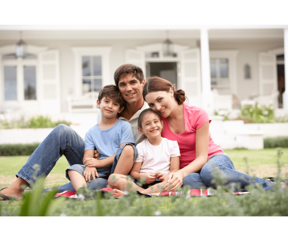 A happy Palm Bay family sits on their beautiful green lawn in front of their pest-free home.