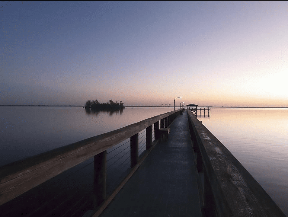 A tranquil view of the pier on the Indian River Lagoon near Micco, Florida, at sunset.