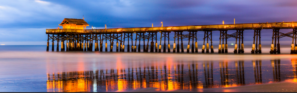 The Cocoa Beach Pier at night, with lights reflecting on the water.