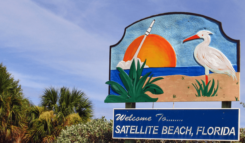 Welcome sign for Satellite Beach, Florida, with a stylized egret and a rocket launch.