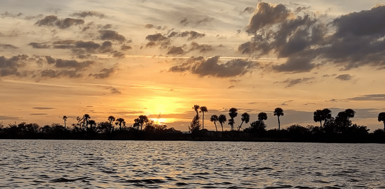 Sunset over the Banana River with palm trees in Indian Harbour Beach.